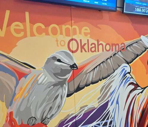 mural on wall that says, "welcome to oklahoma," with bird in flight and native american