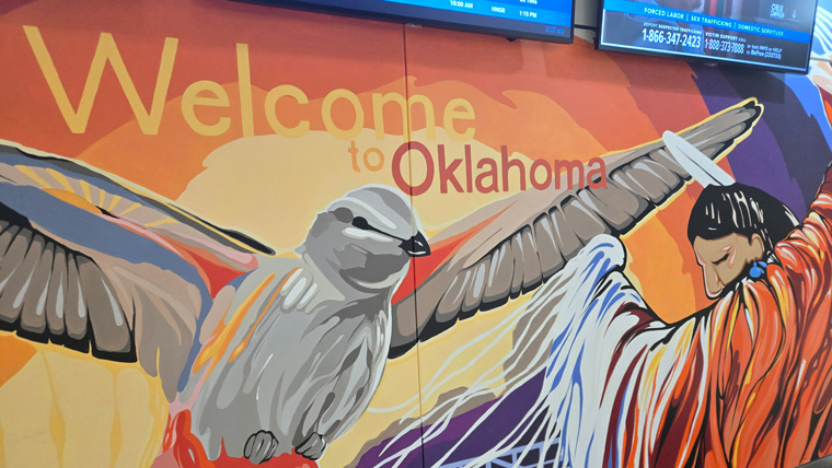 mural on wall that says, "welcome to oklahoma," with bird in flight and native american