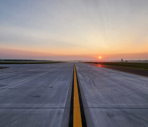 view looking down a runway with the sunset in the background