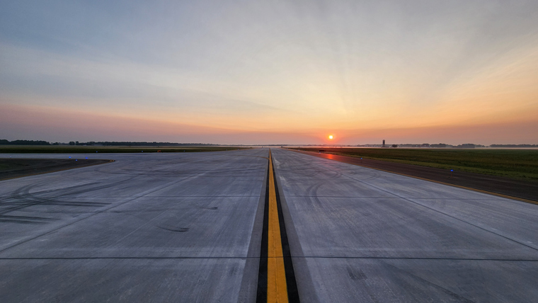 view looking down a runway with the sunset in the background