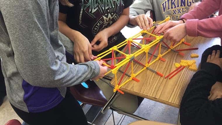 Children in STEM building toy bridge