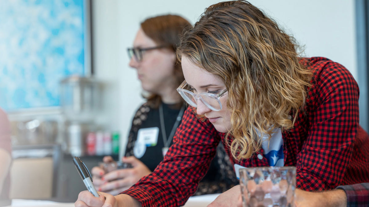 erin kelly looks diligently at what she is writing on a paper during an ERG gathering