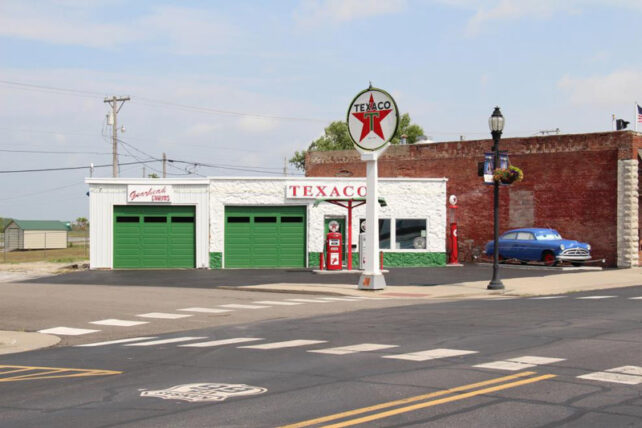 a green and white garage with an old fashioned Texaco sign out front