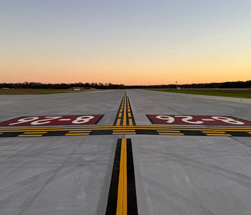 Looking down an airport taxiway with a sunset in the background