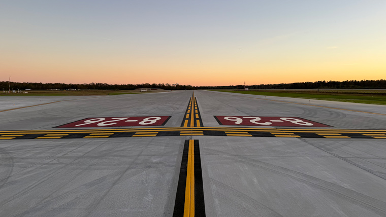 Looking down an airport taxiway with a sunset in the background