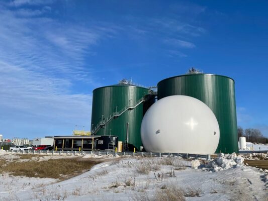 Two large, green digesters on a winter day