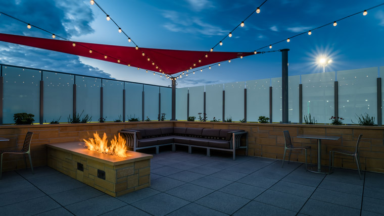 the terrace at dusk with bulb lights and a fire pit