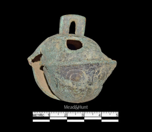 Old brass horse bell, with signs of rust, against a black background