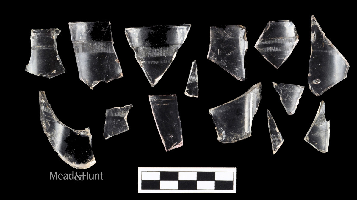 Various glass jelly juice jar fragments displayed against a black backdrop. Some have patterns and bands.