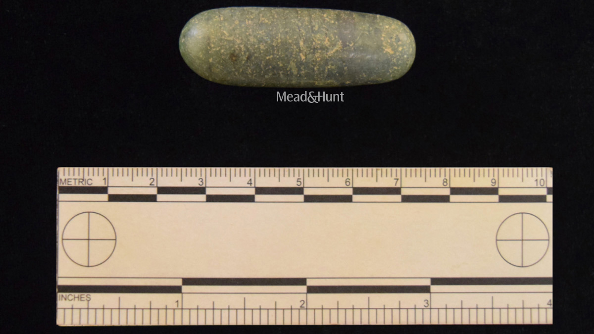Image of long round green tool next to a measuring stick