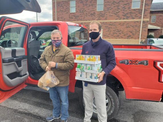 Jamie and Aaron carry canned goods outside of a feed bank