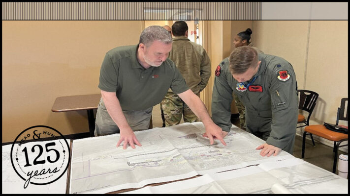 Tim murphy looks over drawings spread on a table with a man in uniform