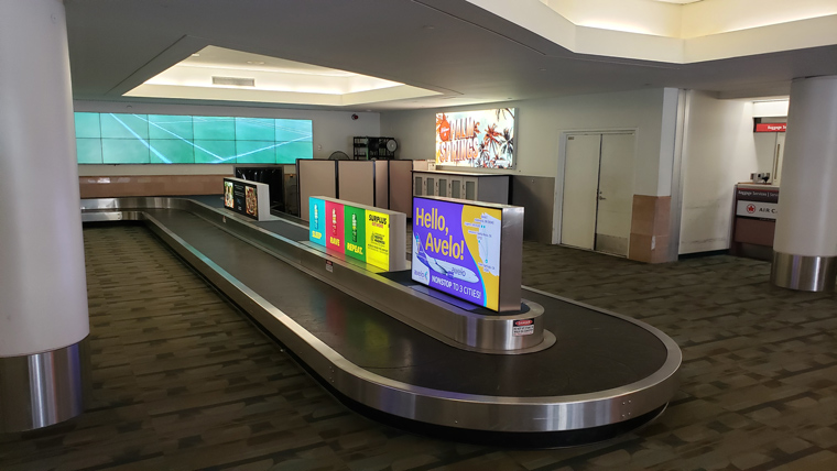 baggage claim with stylized welcome sign behind it