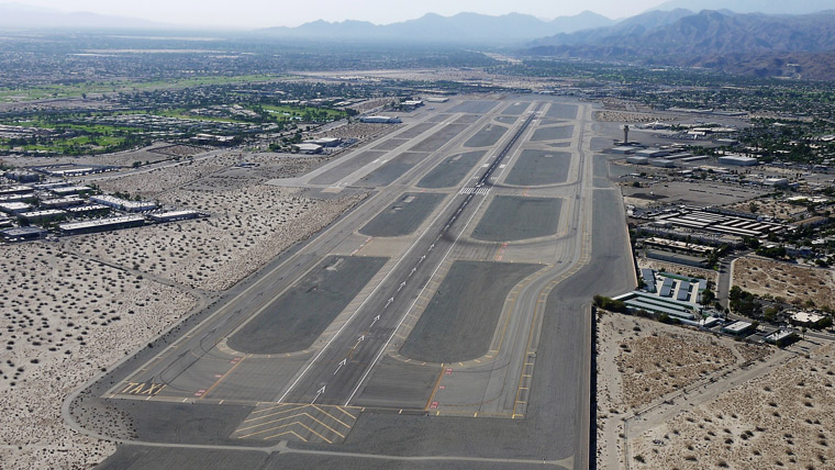 aerial view of taxiway and runway with mountains in the background