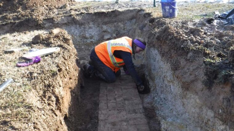 Archeologist digs up a brick in a pit