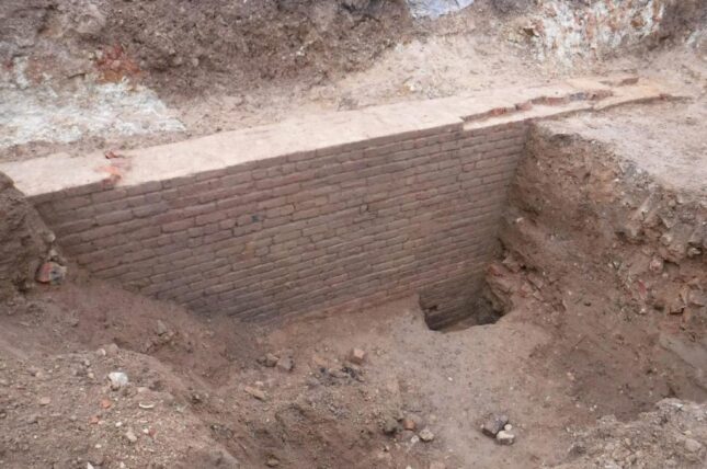 A deep pit that exposes a wall of brick