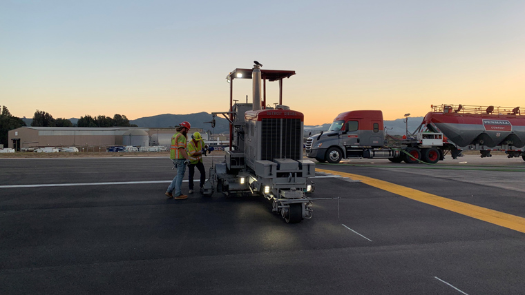 grooving equipment on pavement with two construction workers