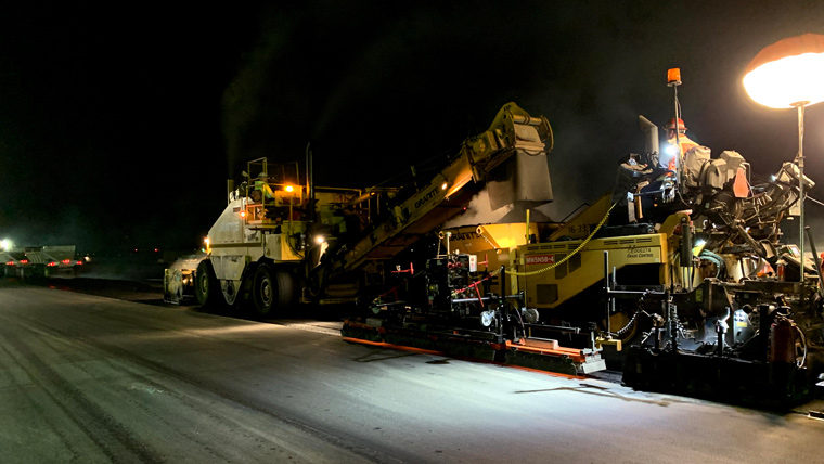 paving equipment on runway at night