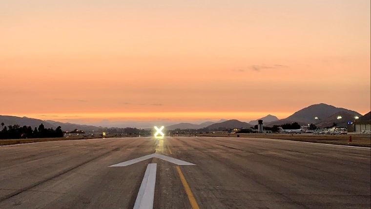 view looking down runway with lit up "X" at the end and sunset in background