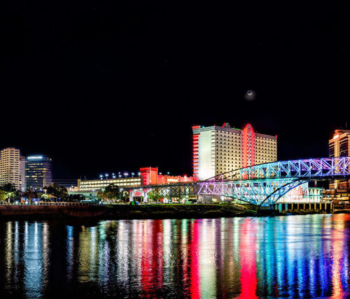 skyline of SHV at night, multicolor city lights reflecting on water