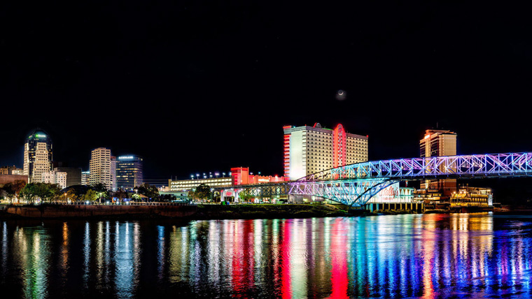 skyline of SHV at night, multicolor city lights reflecting on water