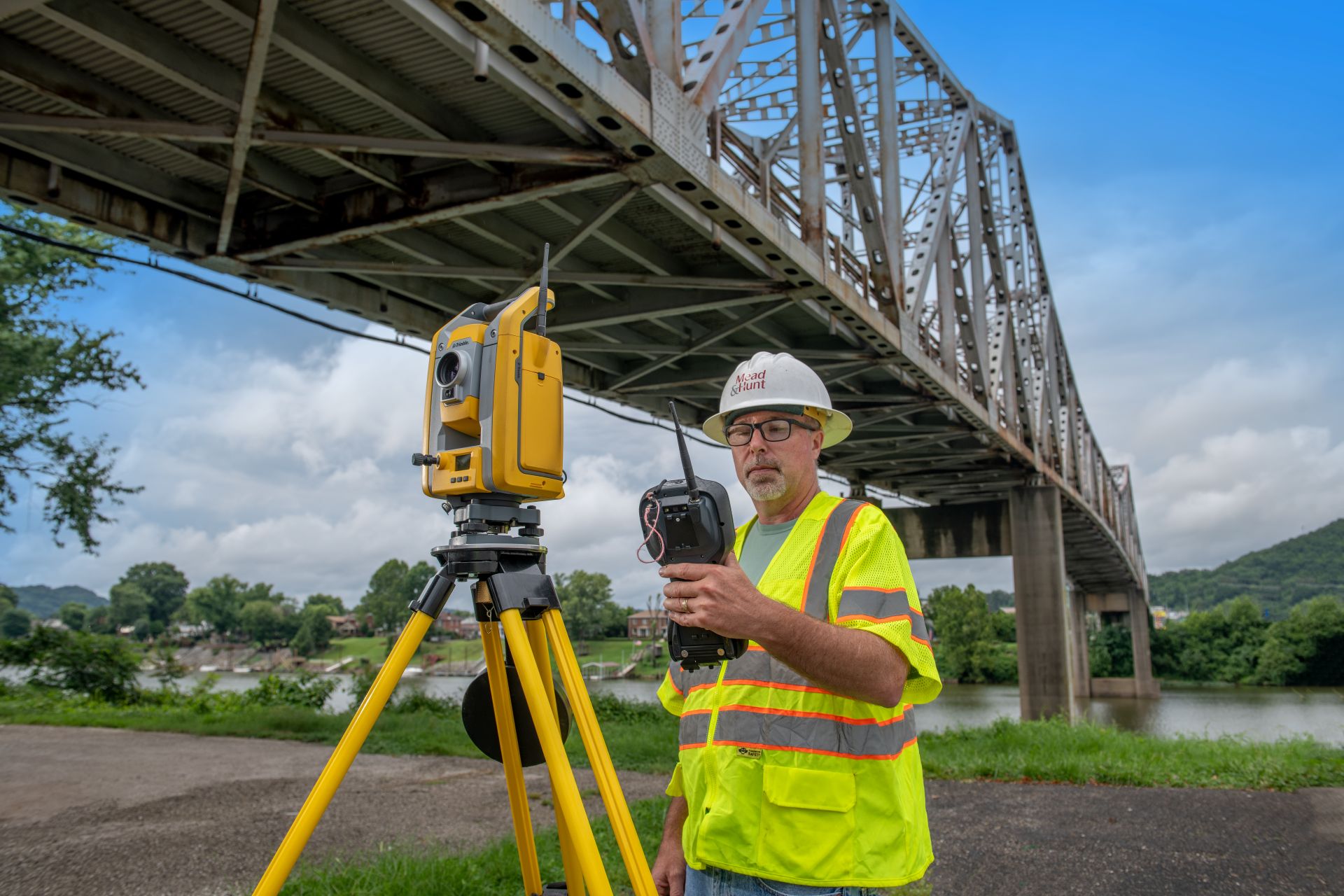 A mead and hunt employee in a safety vest and helmet works with equipment at a project