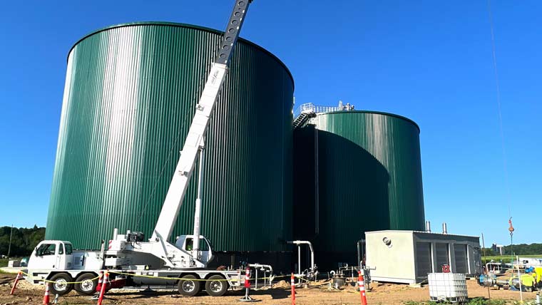Two large green tanks with a crane truck