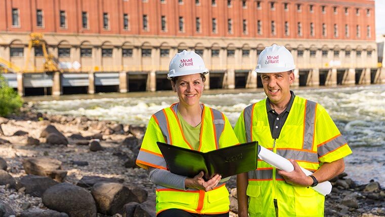 Jen Schuetz and Gary Ruchti stand in front of Dam facility