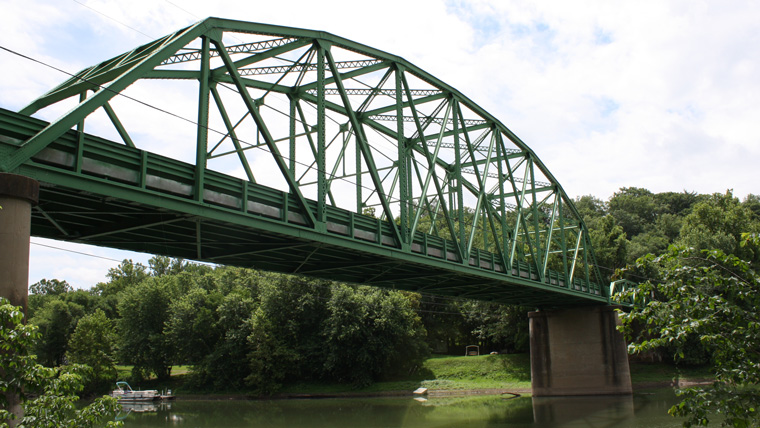 green metal bridge over a waterway