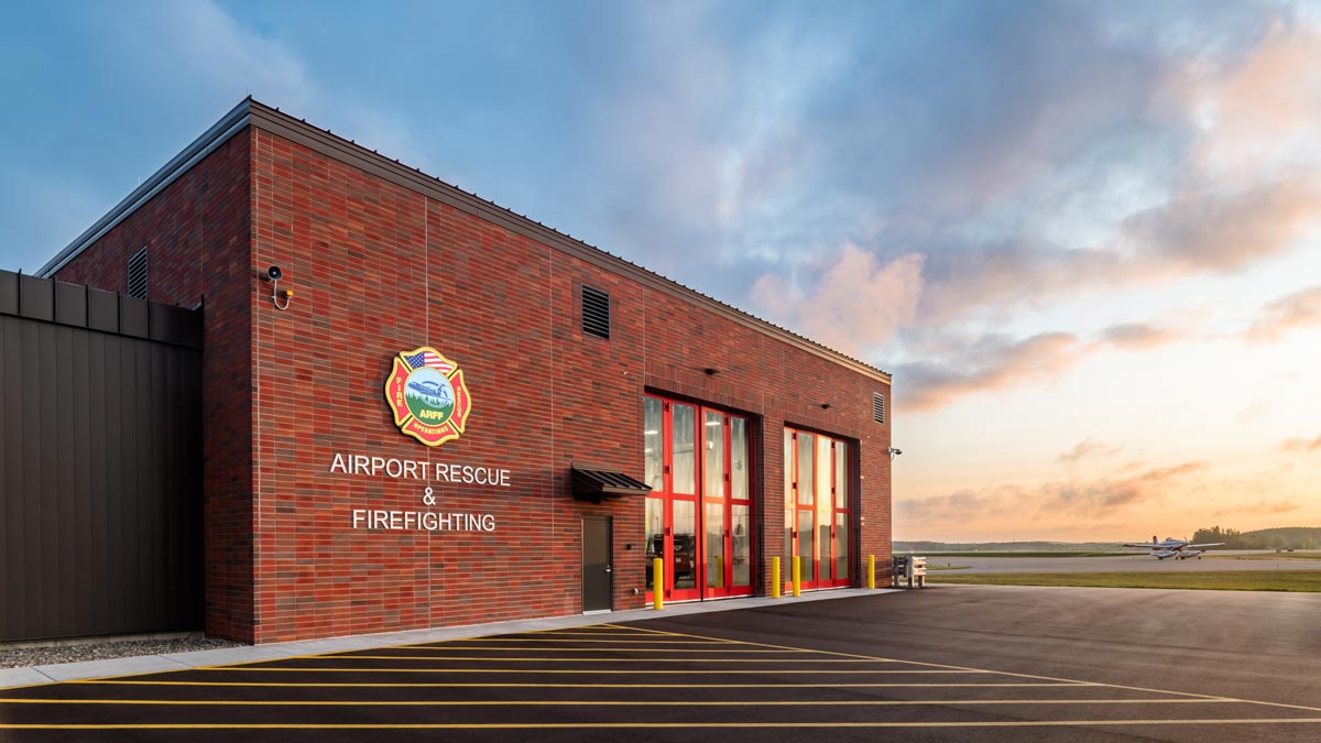 Brainerd Lakes Airport Rescue and Firefighting building with red brick and large glass doors for vehicle pass through at dusk