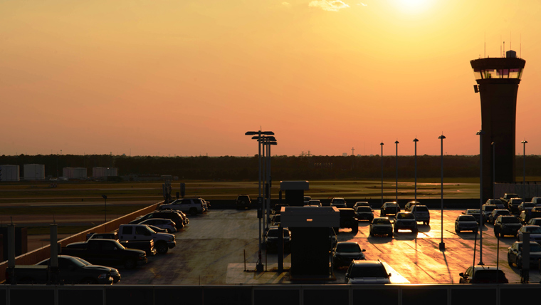 IAH airport, control tower to right, parking lot in foreground, orange sunset in background