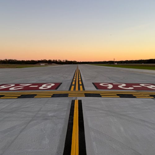 Looking down an airport taxiway with a sunset in the background
