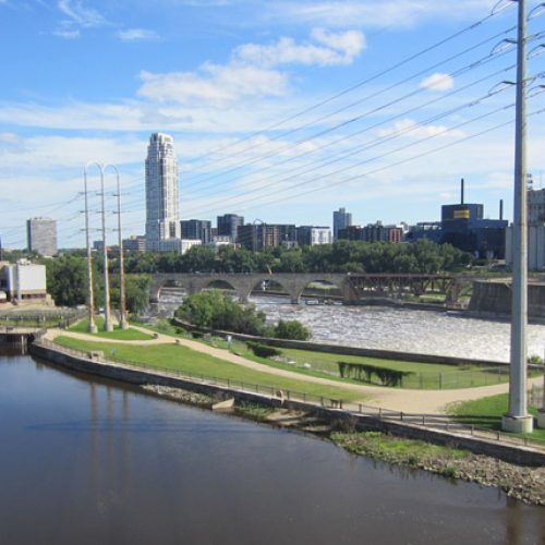 cityscape with body of water in foreground with dam to the right