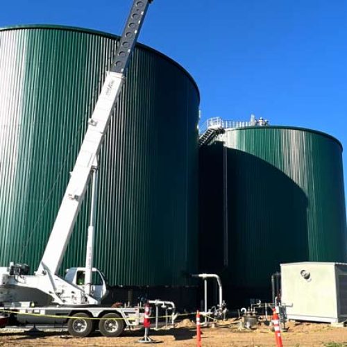 Two large green tanks with a crane truck