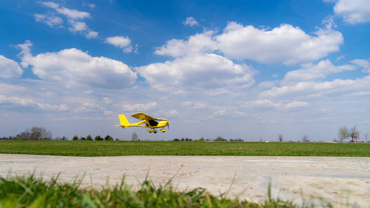 a small yellow plan is about to touch down on a runway on a sunny, clear day