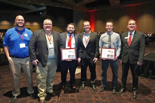 six employees post with plaques at the awards banquet