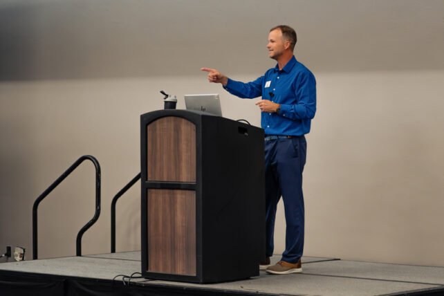 jamie stands at a podium calling on someone from the audience