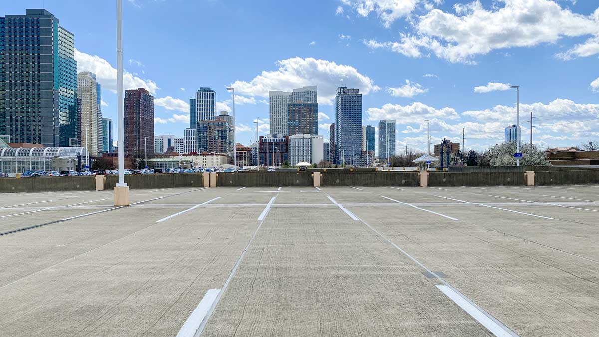 empty parking lot in front of a city skyline under blue skies with fluffy clouds