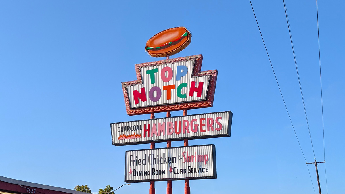 a fifties style neon sign says Top Notch hamburgers on stacked, colorful signss