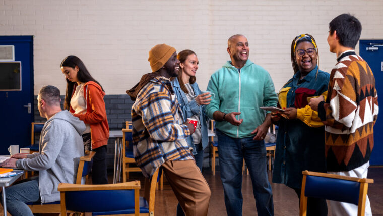 people gather together in a large open space happily engaged in conversation with food and drinks