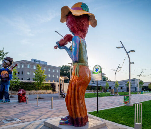 a larger than life sculpture depicts an Appalachian woman playing a fiddle in Slack Plaza