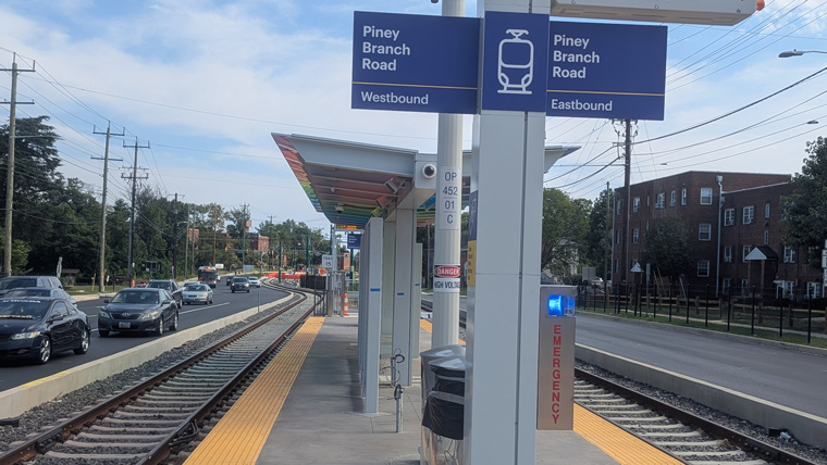 metro rail stop with signs, next to road